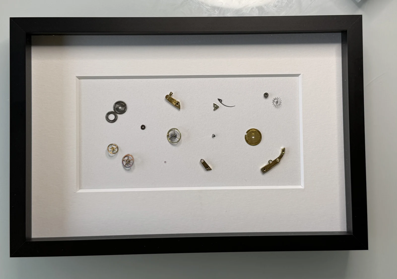 Gerahmtes Kunstwerk aus Uhrenteilen mit dunklem Rahmen