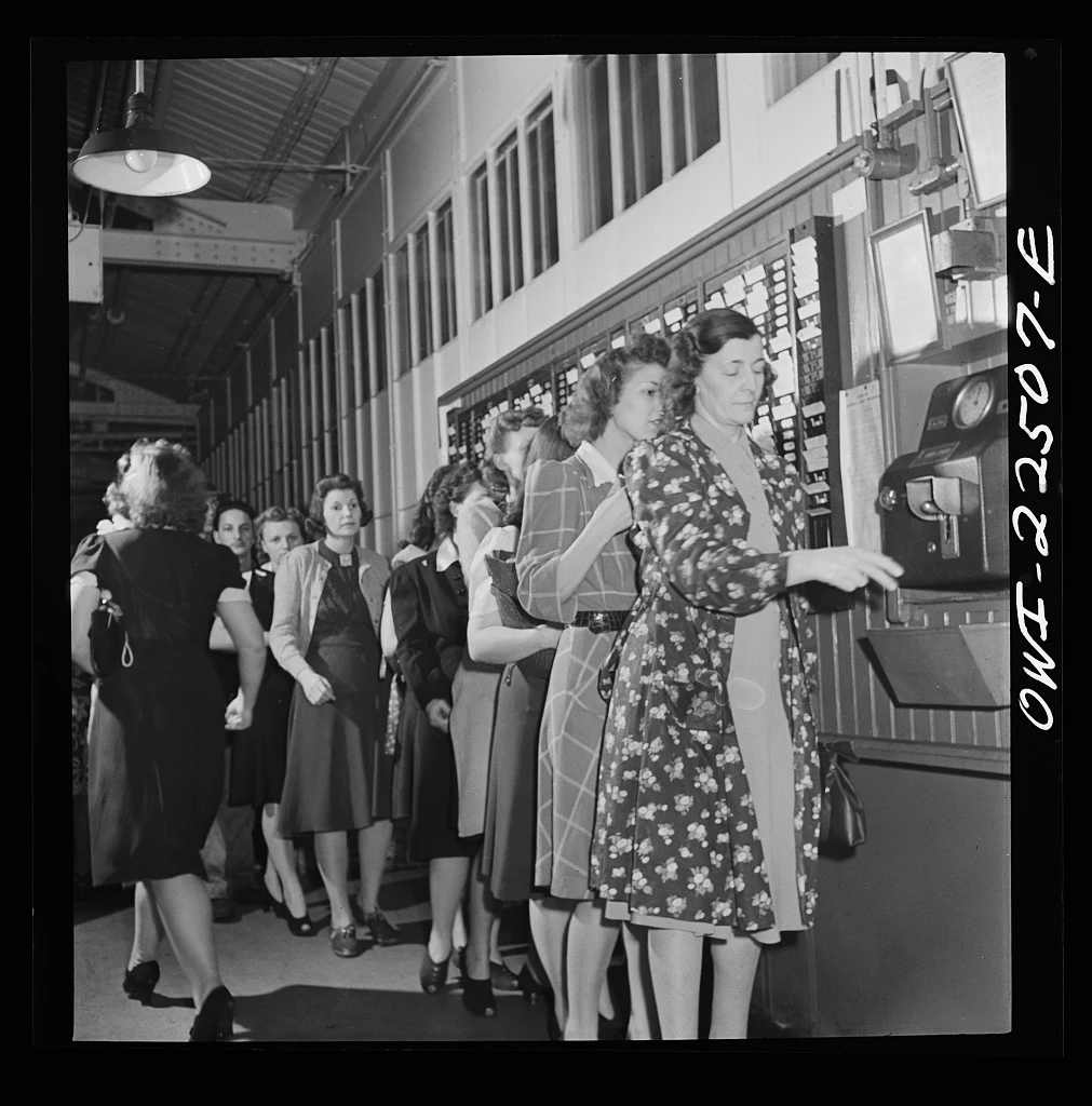 Women workers queue inside a factory to punch their cards in a mechanical time clock